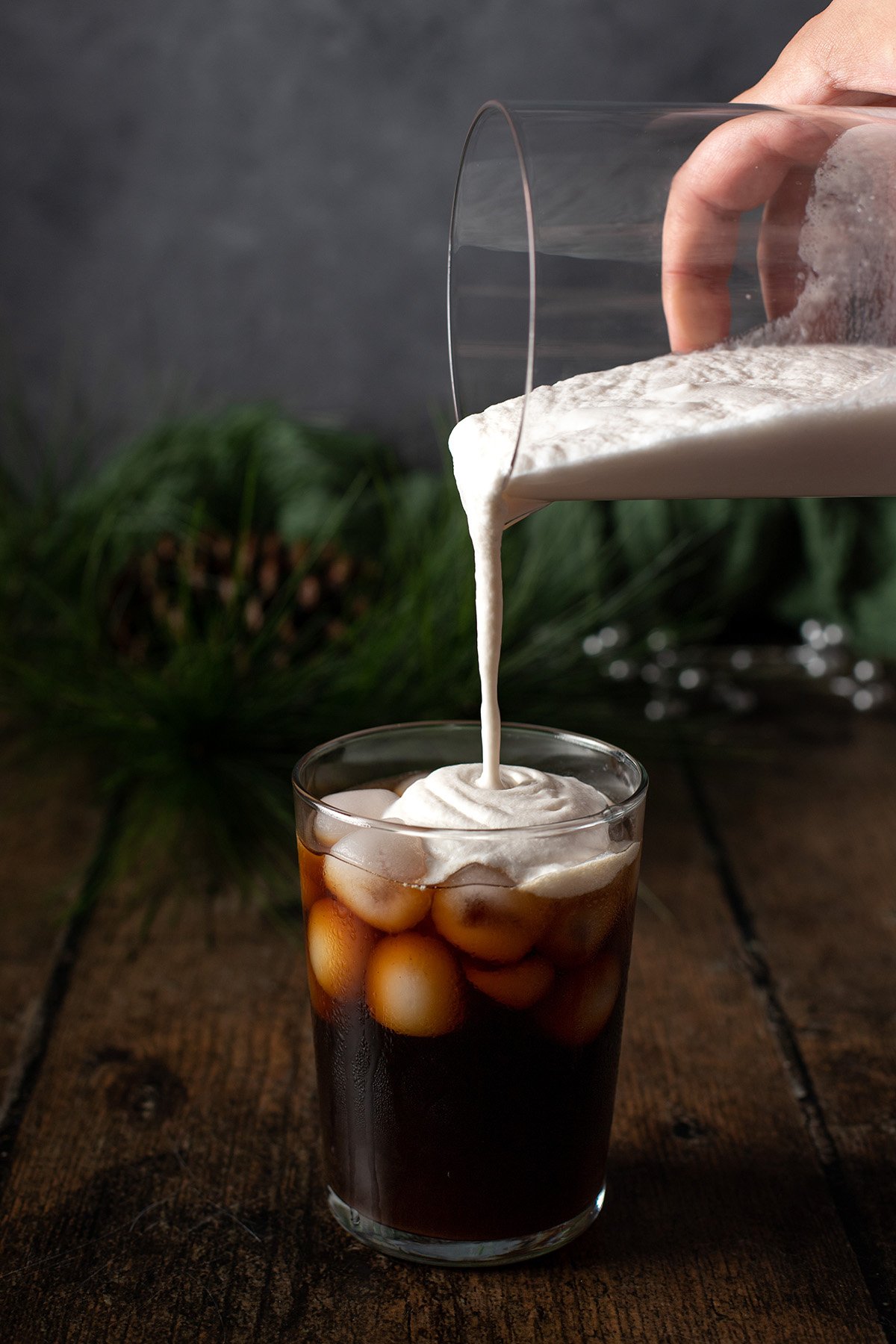 irish cream cold foam being poured onto a glass of cold brew