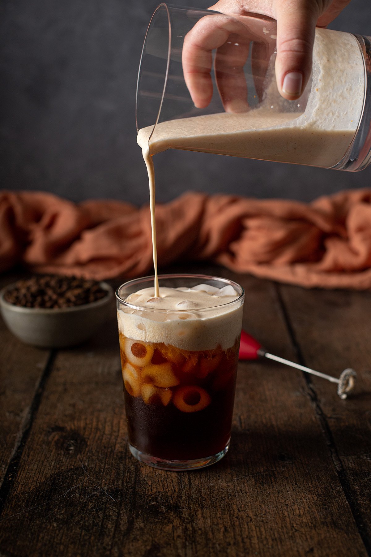 pumpkin cream cold foam being poured onto a glass of cold brew