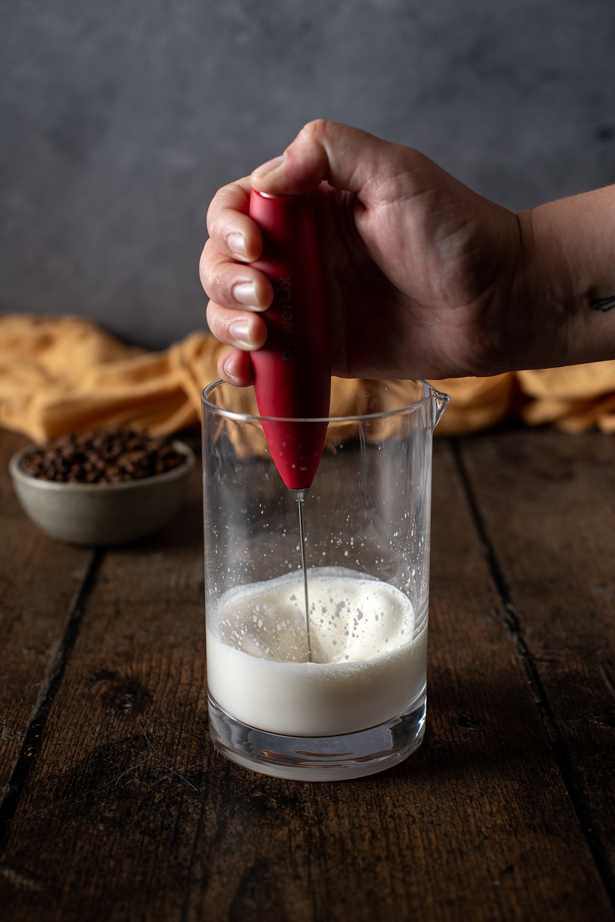 salted caramel cream cold foam being made in a glass jar with a handheld milk frother