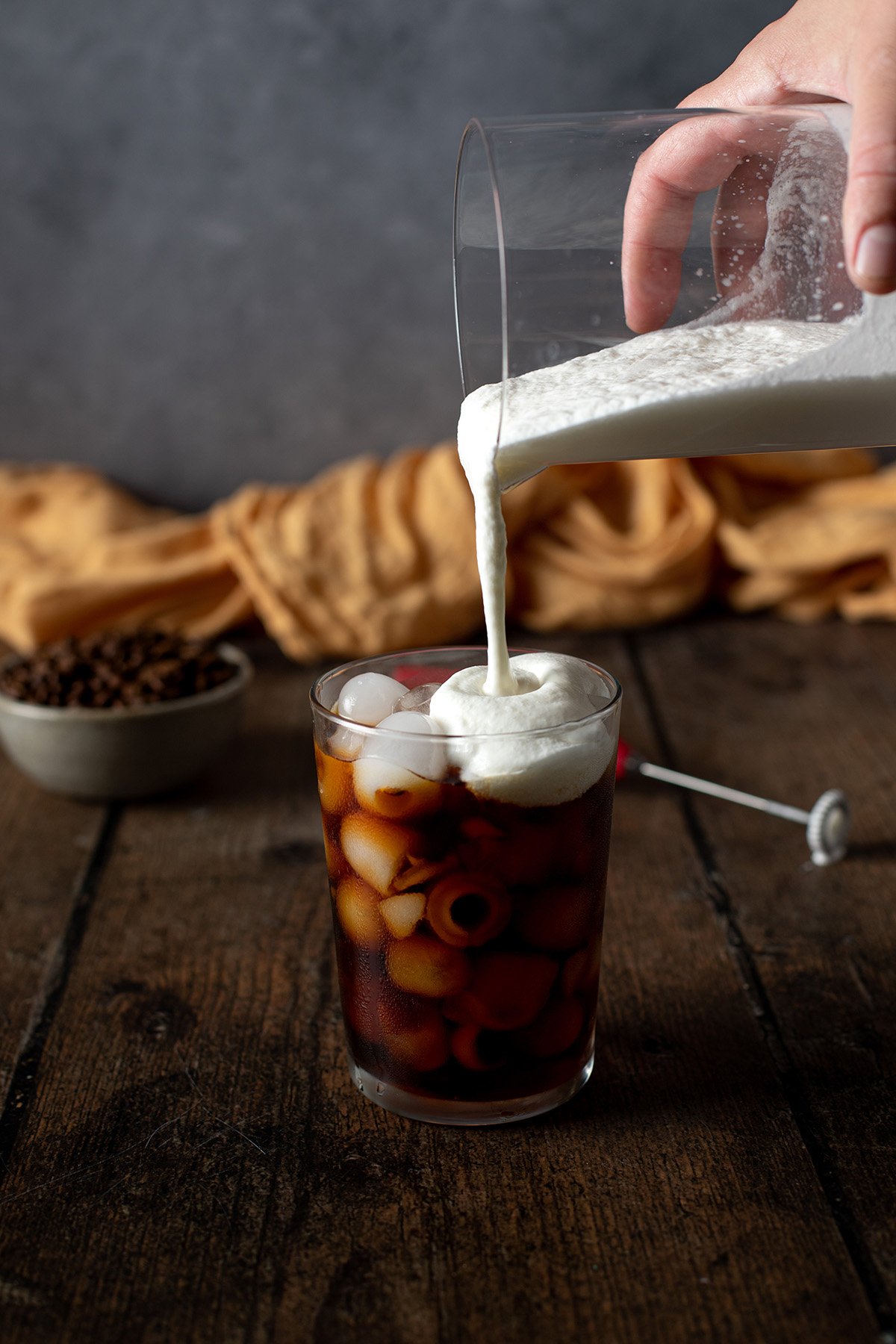 salted caramel cream cold foam being poured onto a glass of cold brew cofee