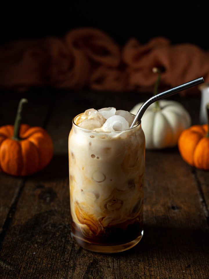 an iced pumpkin spice latte with a metal straw