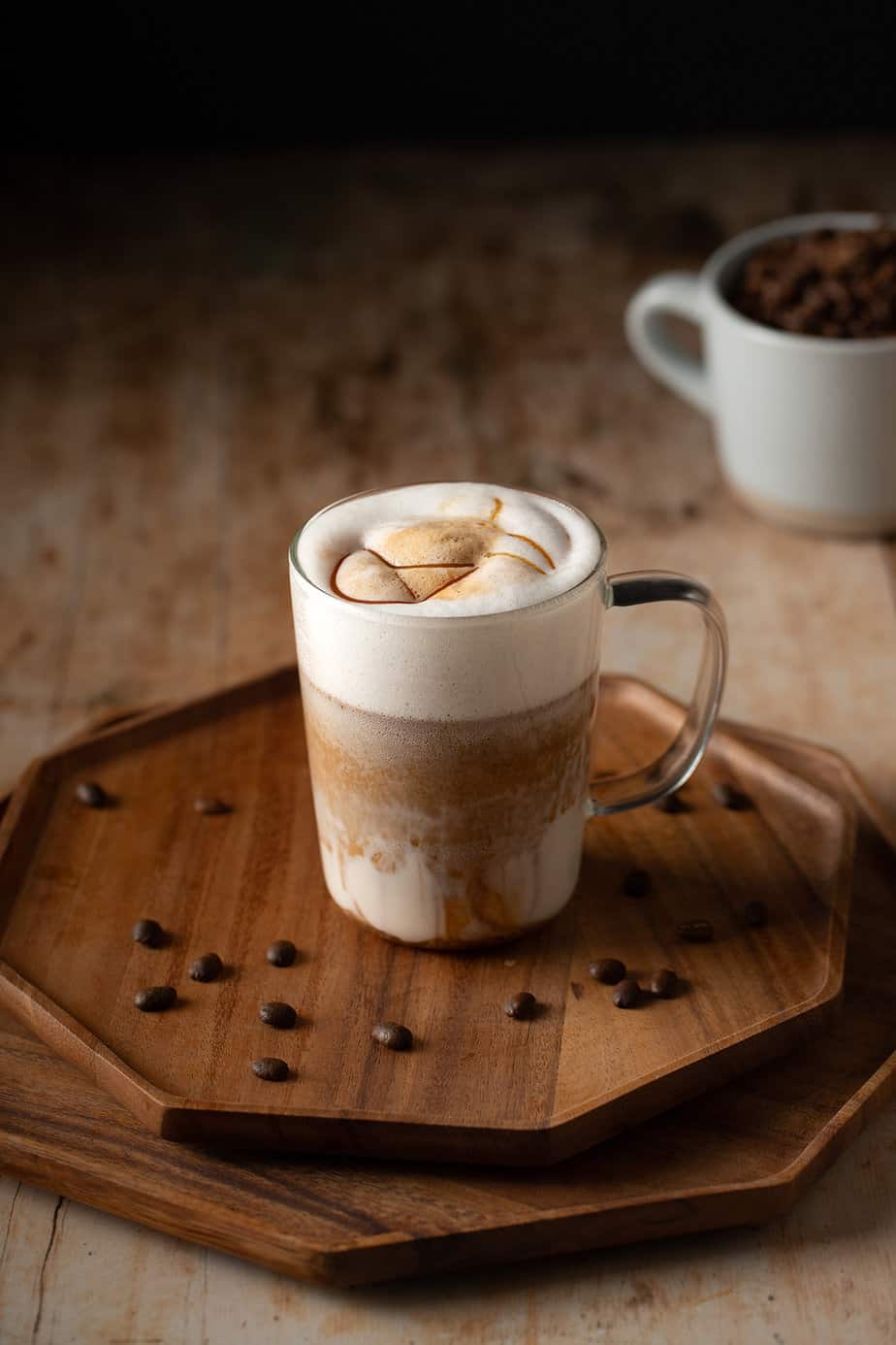 a caramel macchiato in a glass mug, with caramel drizzle on top