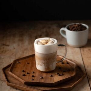 a caramel macchiato in a glass mug, with caramel drizzle on top