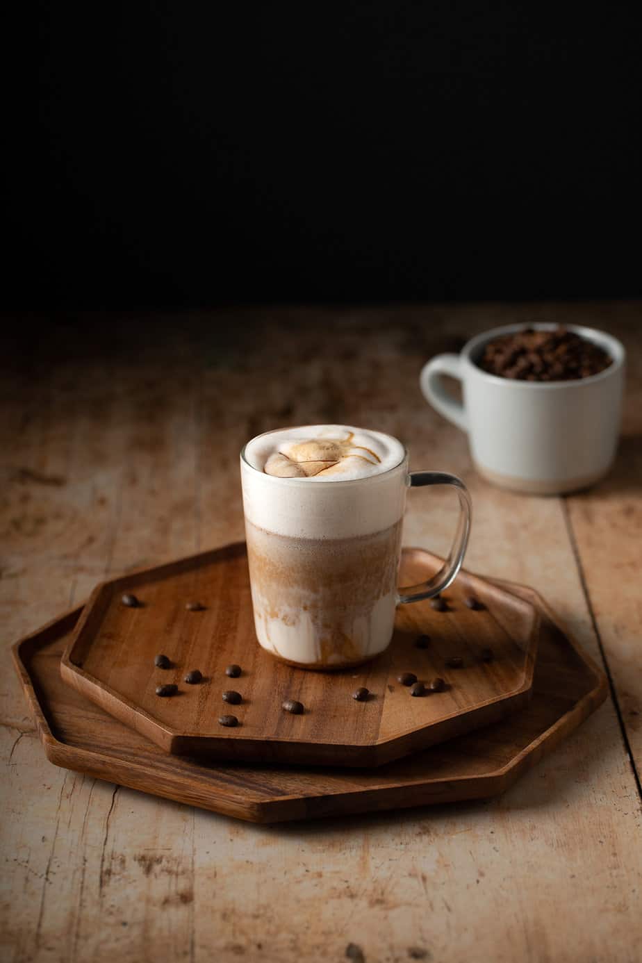 a caramel macchiato in a glass mug, with caramel drizzle on top