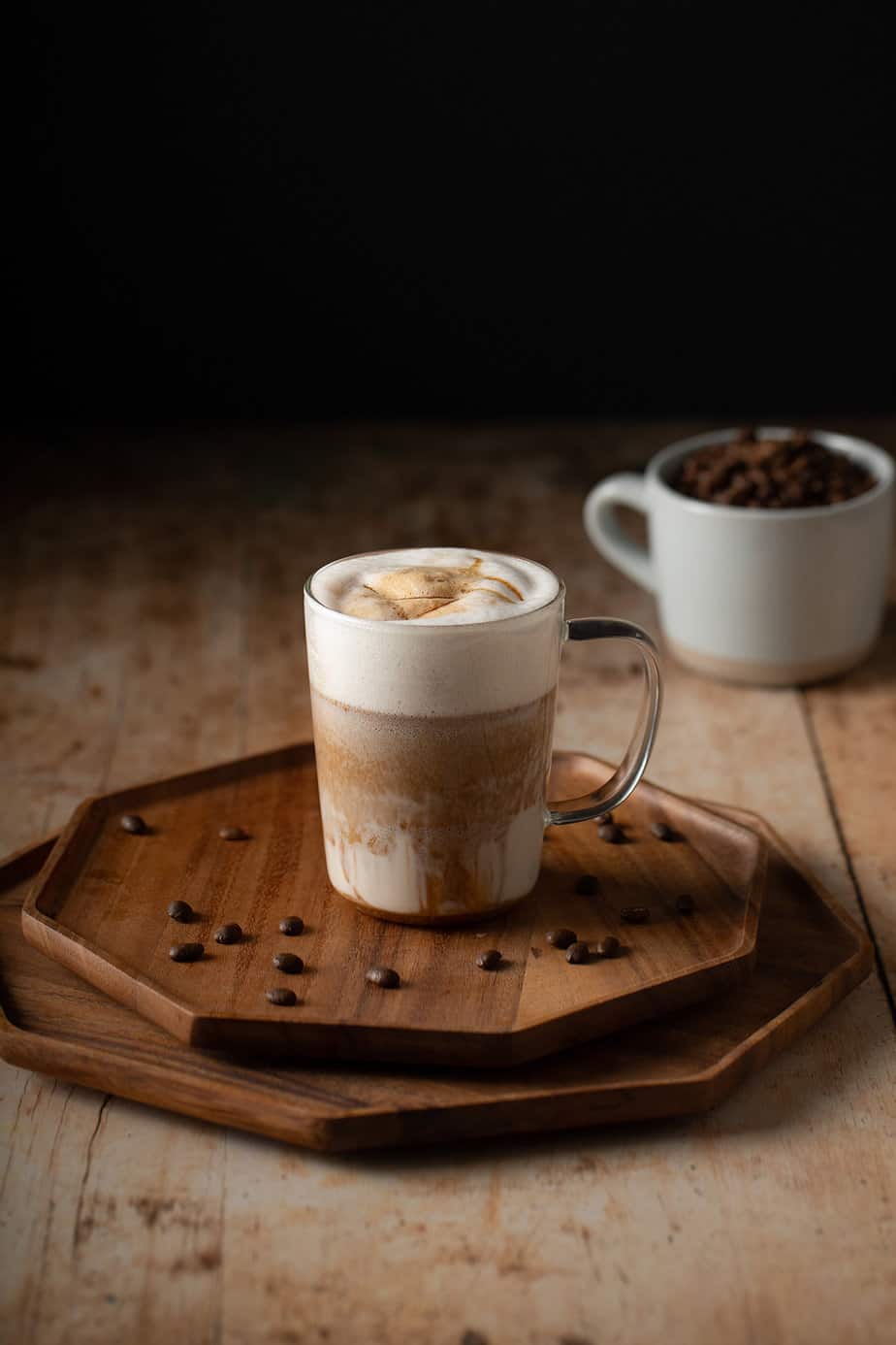 a caramel macchiato in a glass mug, with caramel drizzle on top