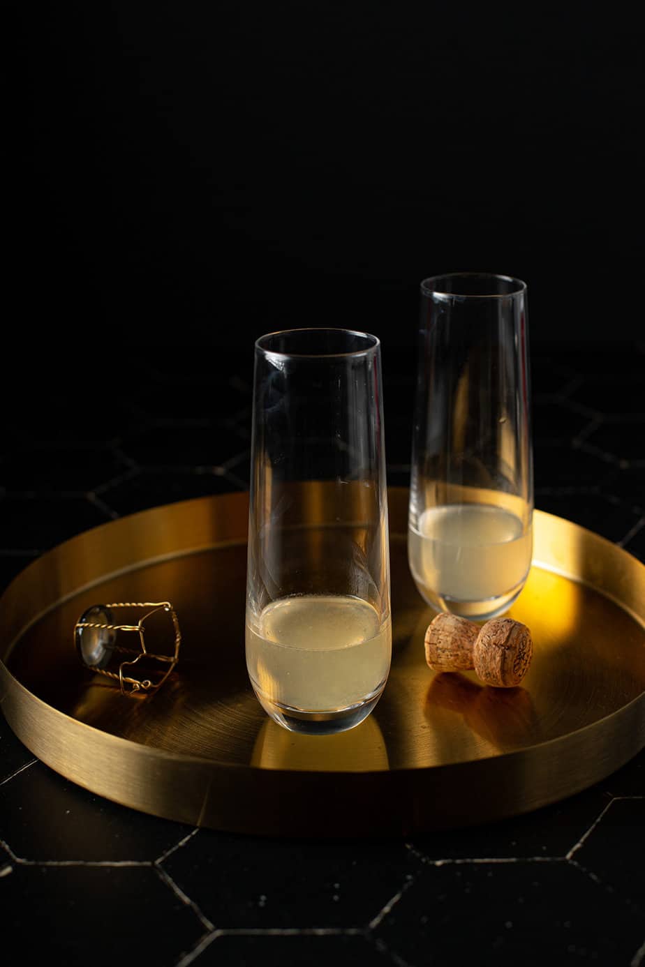two stemless champagne flutes on a gold serving tray