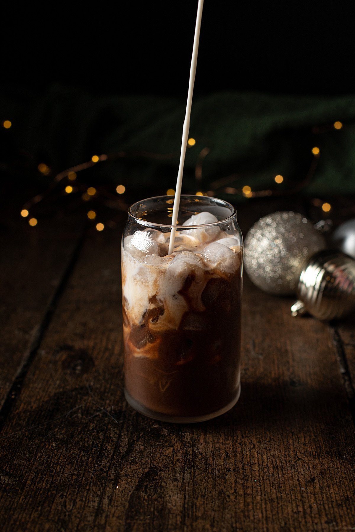 oat milk being poured into an iced peppermint mocha