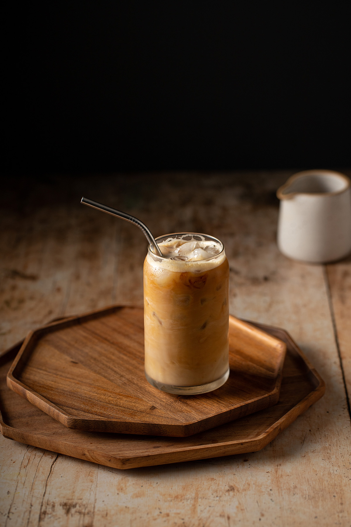 an iced vanilla latte in a glass with a metal straw