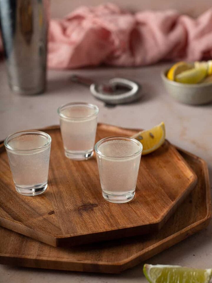 three white tea shots on a brown wooden tray