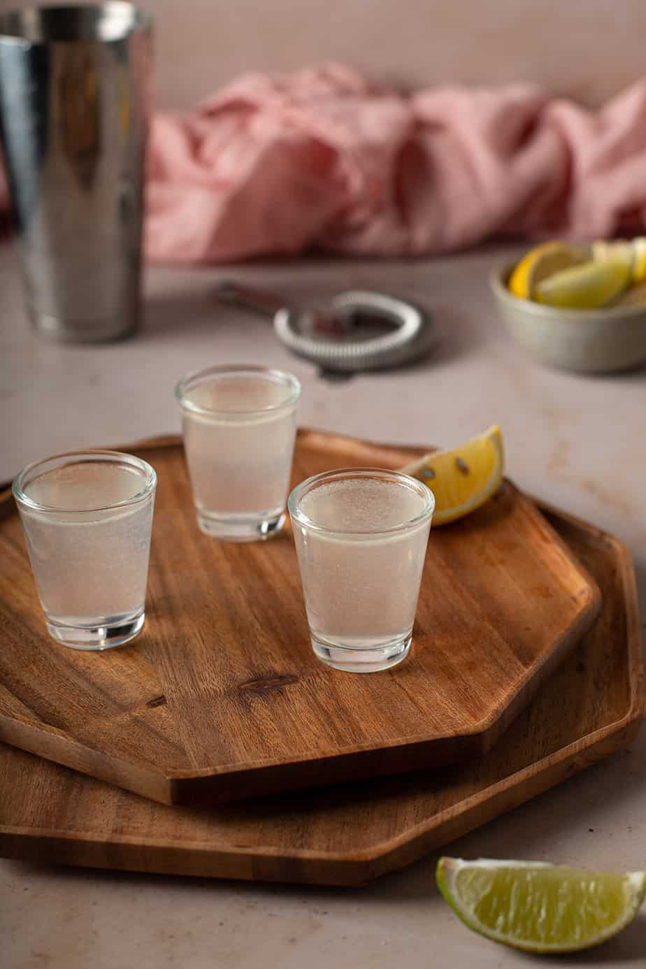 three white tea shots on a brown wooden tray
