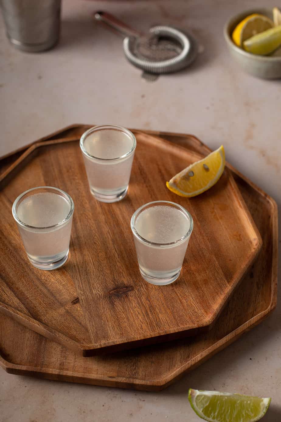 three white tea shots on a brown wooden tray