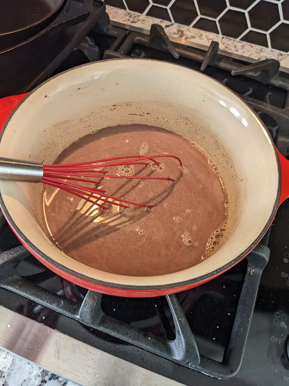 hot chocolate in a saucepan on the stove with a whisk