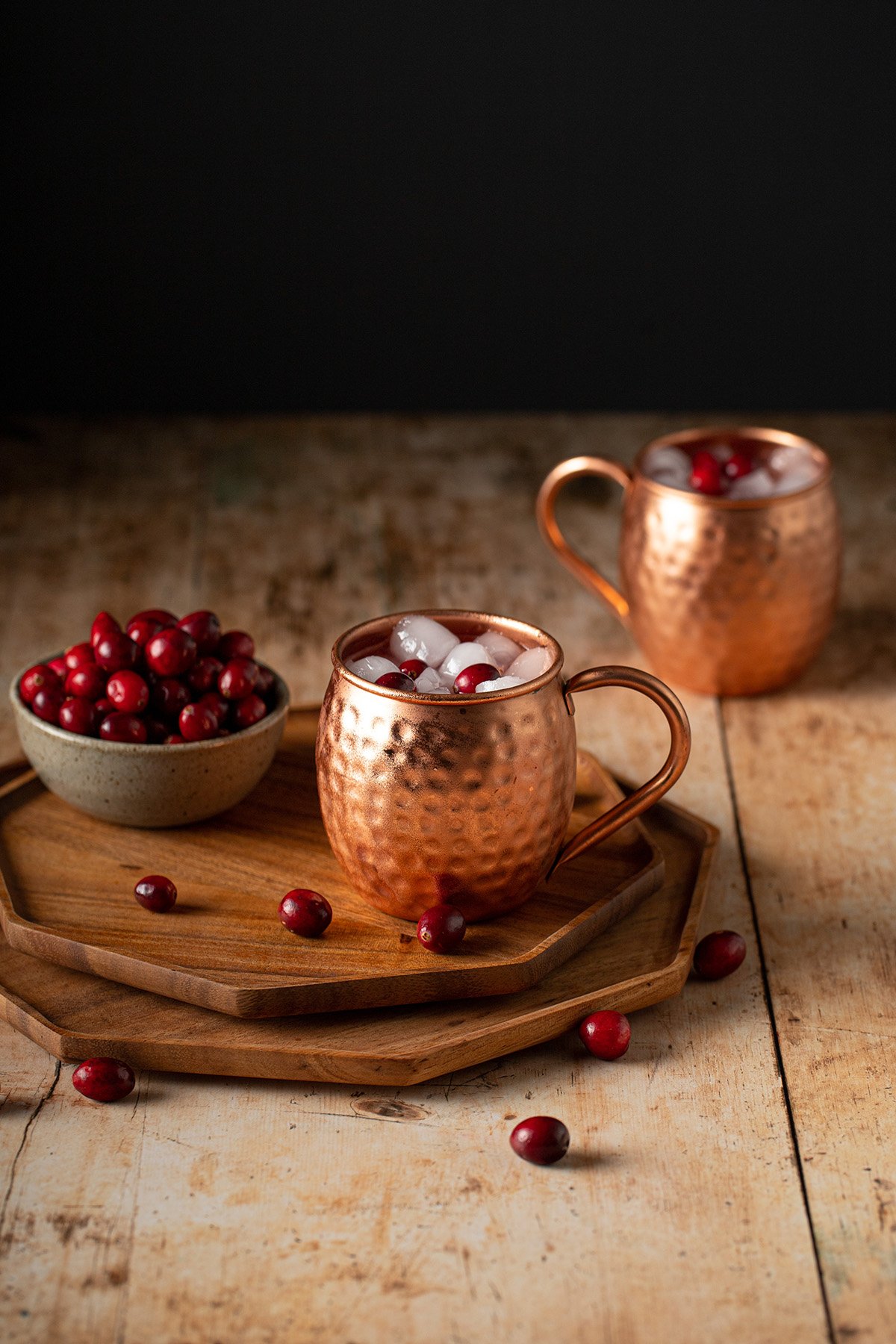 two copper mugs of cranberry moscow mules