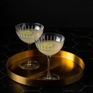 two coupe glasses with french gimlets in them