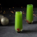 two grinch mimosas in stemless champagne flutes.