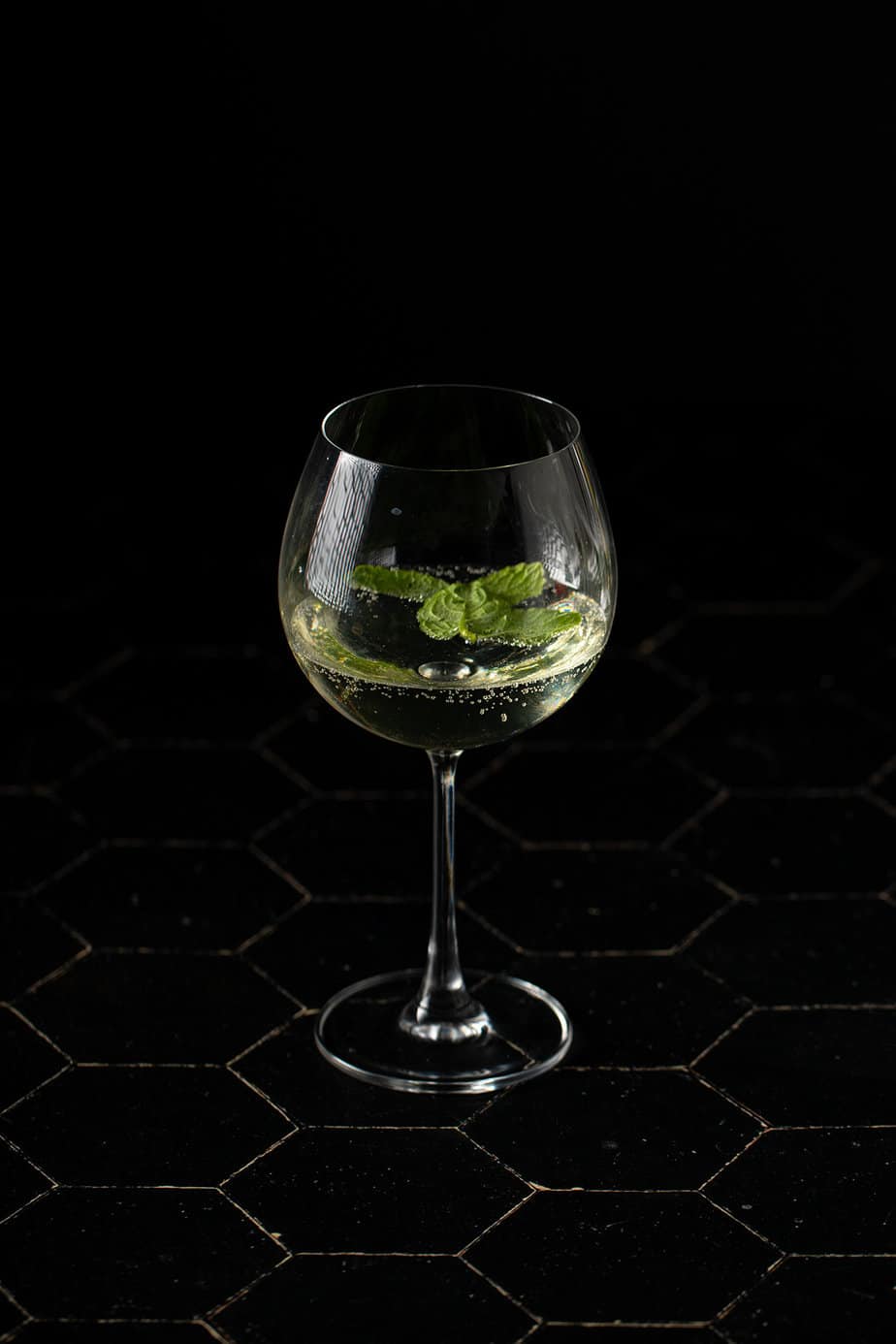 a large wine glass with champagne, soda water, elderflower liqueur, and mint