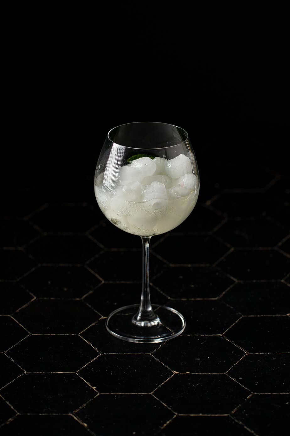 a large wine glass with ice, champagne, and liqueur