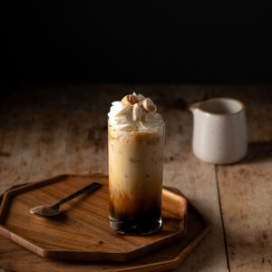 iced cinnamon dolce latte topped with whipped cream on a wooden tray