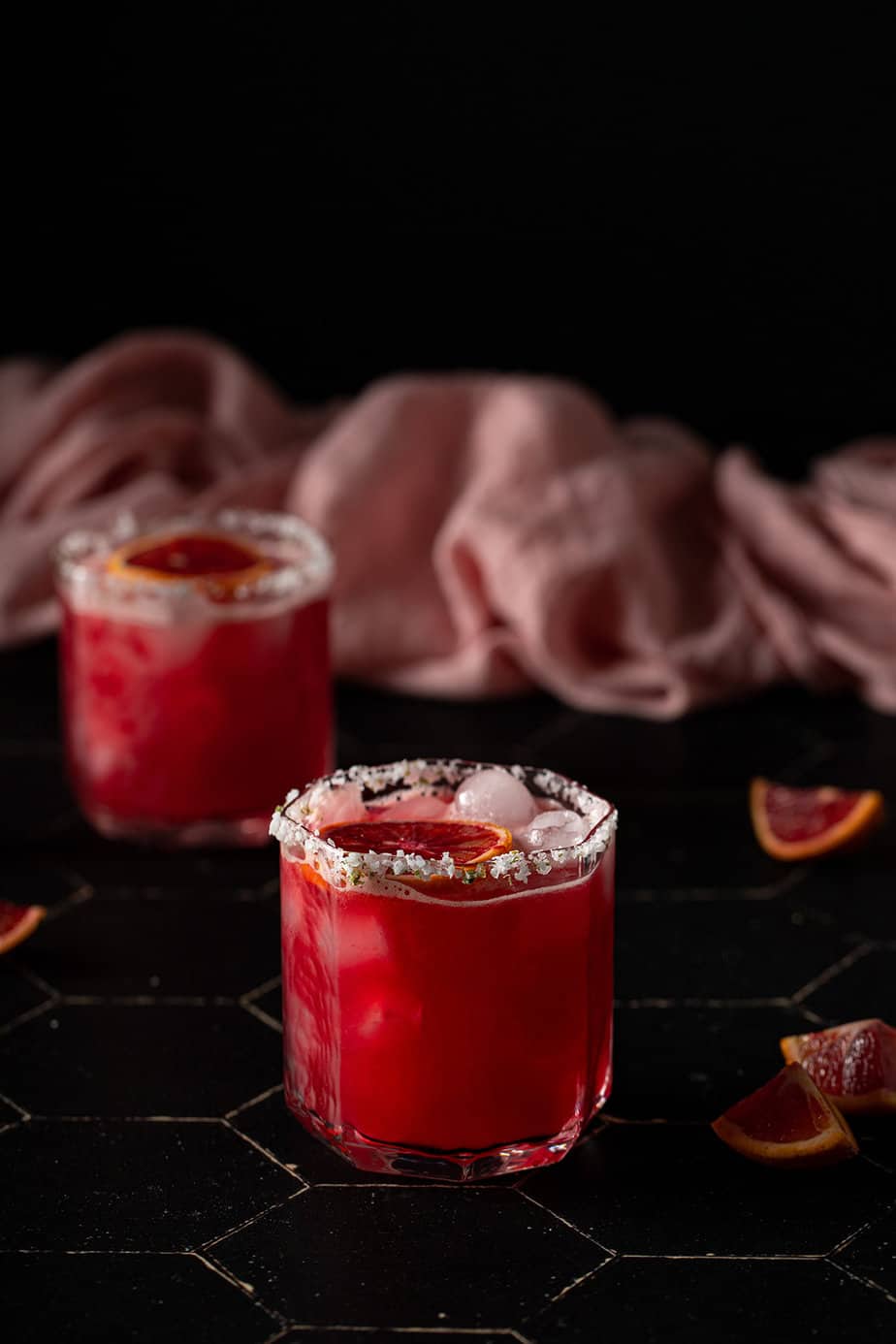 head on view of two short glasses filled with blood orange margaritas