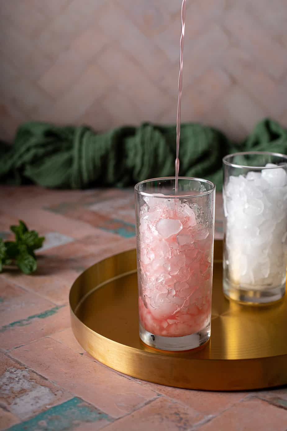 watermelon juice being poured into a tall glass filled with crushed ice