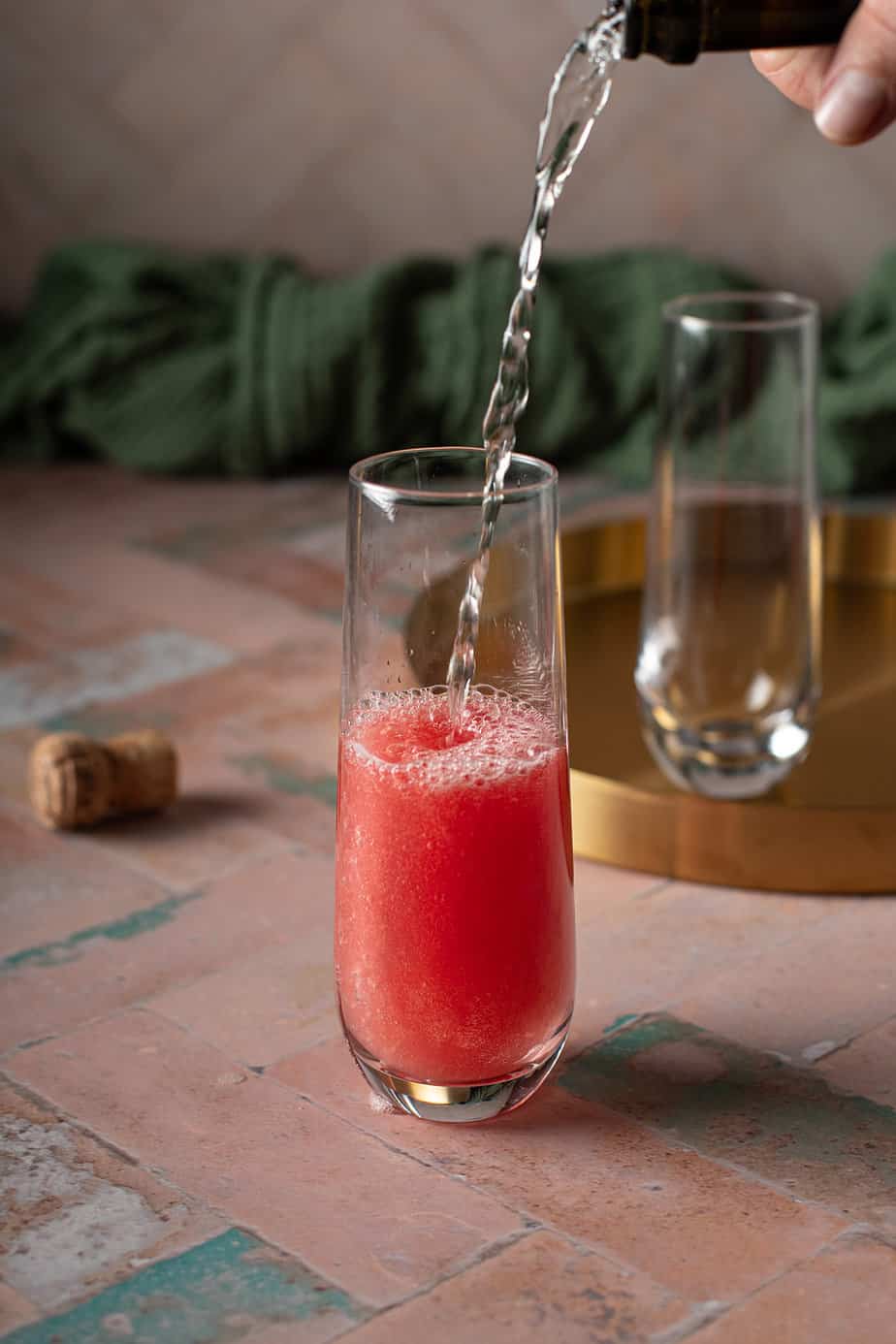 prosecco being poured into a stemless champagne flute with watermelon juice.