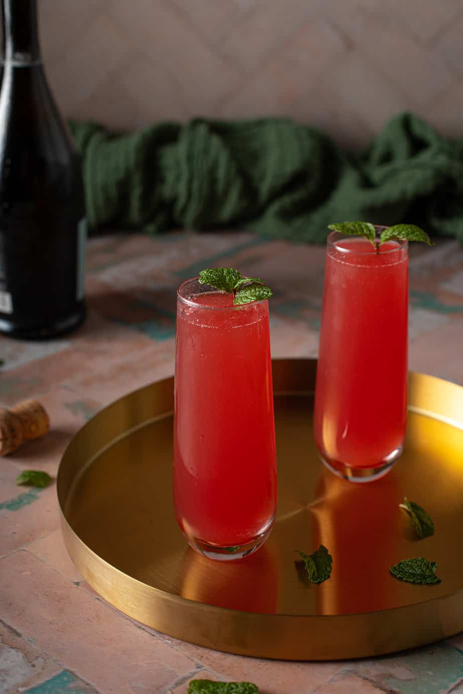two stemless champagne flutes filled with watermelon mimosas on a gold drink tray