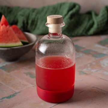 small bottle of watermelon syrup on a pink background