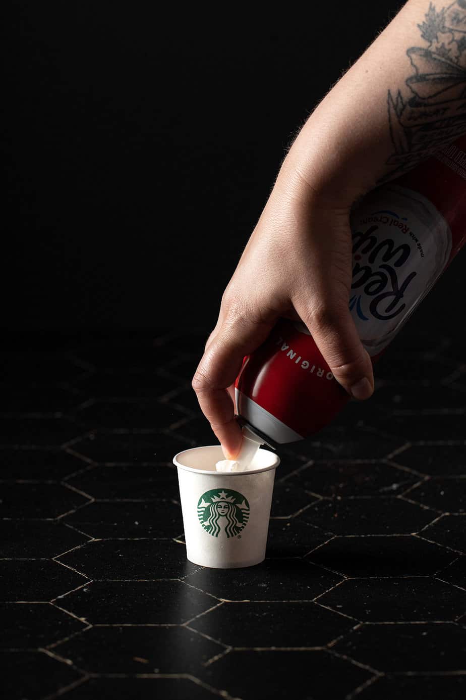 whipped cream being squirted into an espresso cup from starbucks