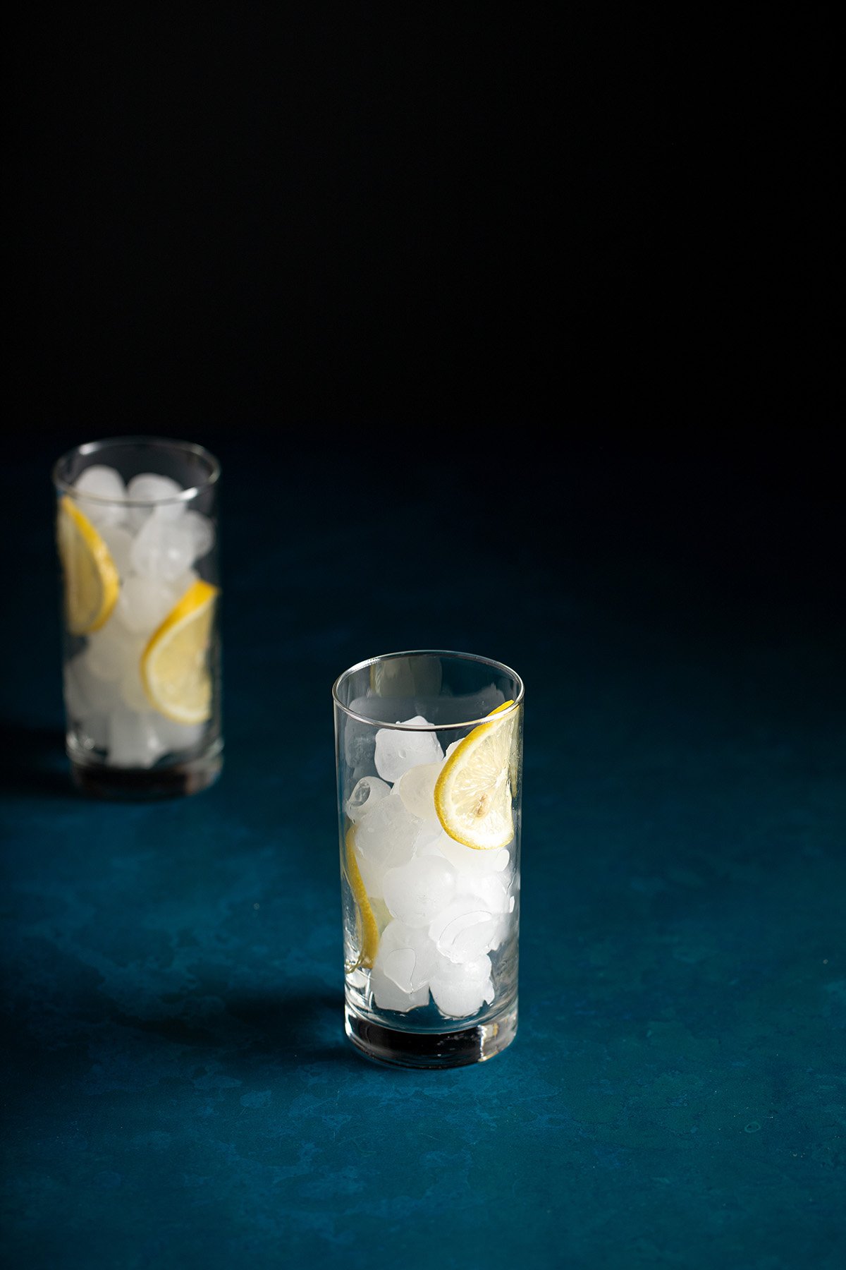 a tall glass full of ice with lemon wheels.