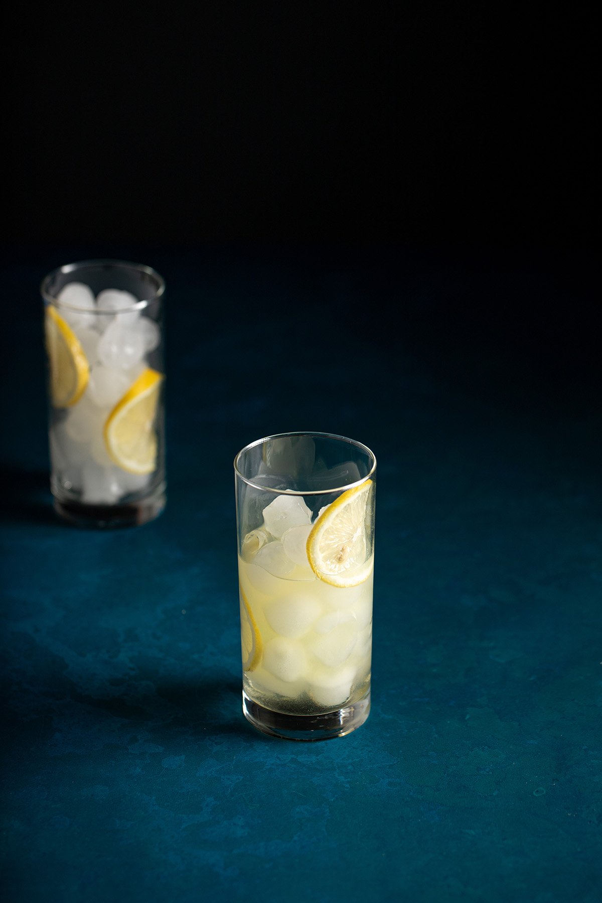 a tall glass filled with ice, lemon wheels, lemon juice, simple syrup, and limoncello.