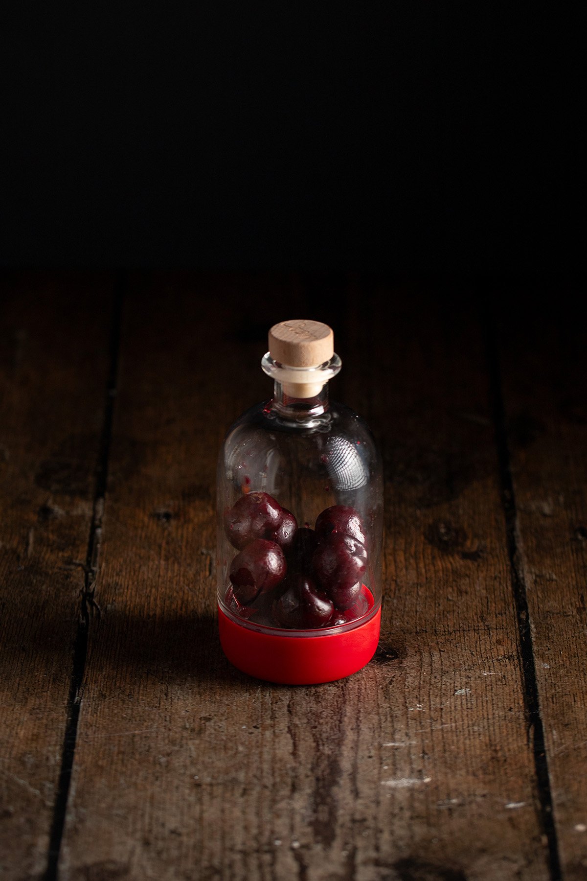 a small bottle with pitted fresh cherries inside.