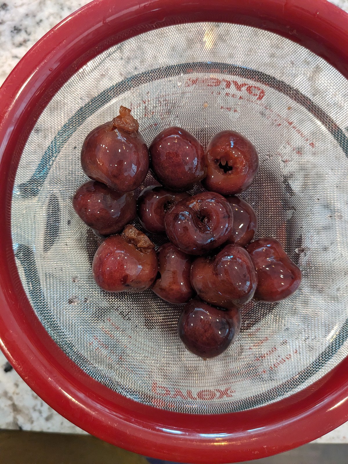 pitted fresh cherries in a fine mesh strainer.