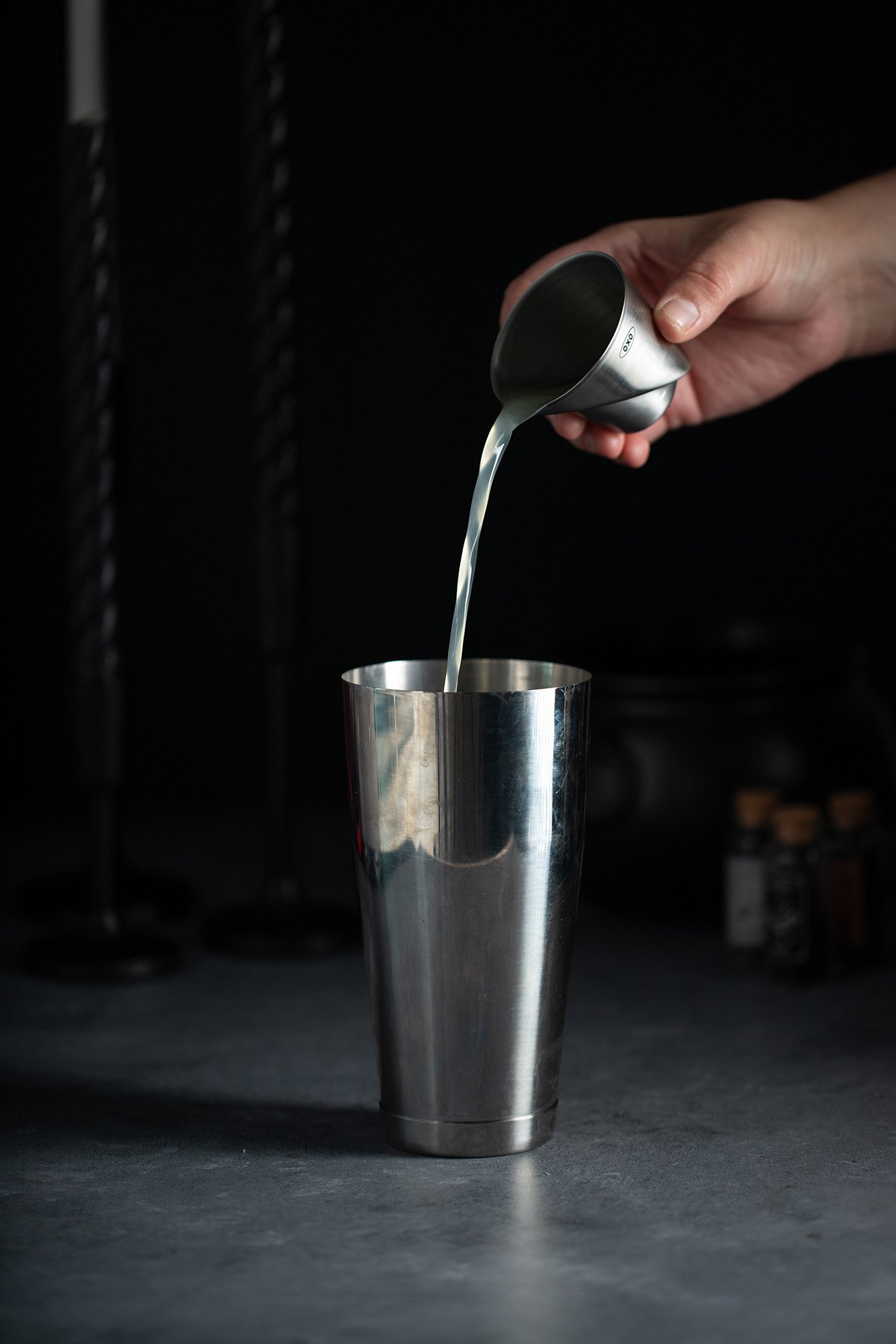 lemon juice being poured into a cocktail shaker.