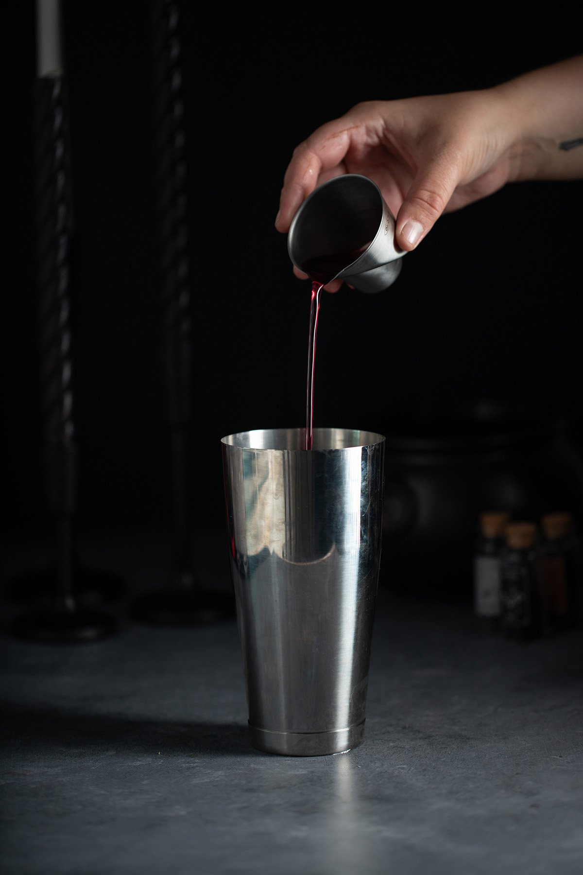 blueberry simple syrup being poured into a cocktail shaker.