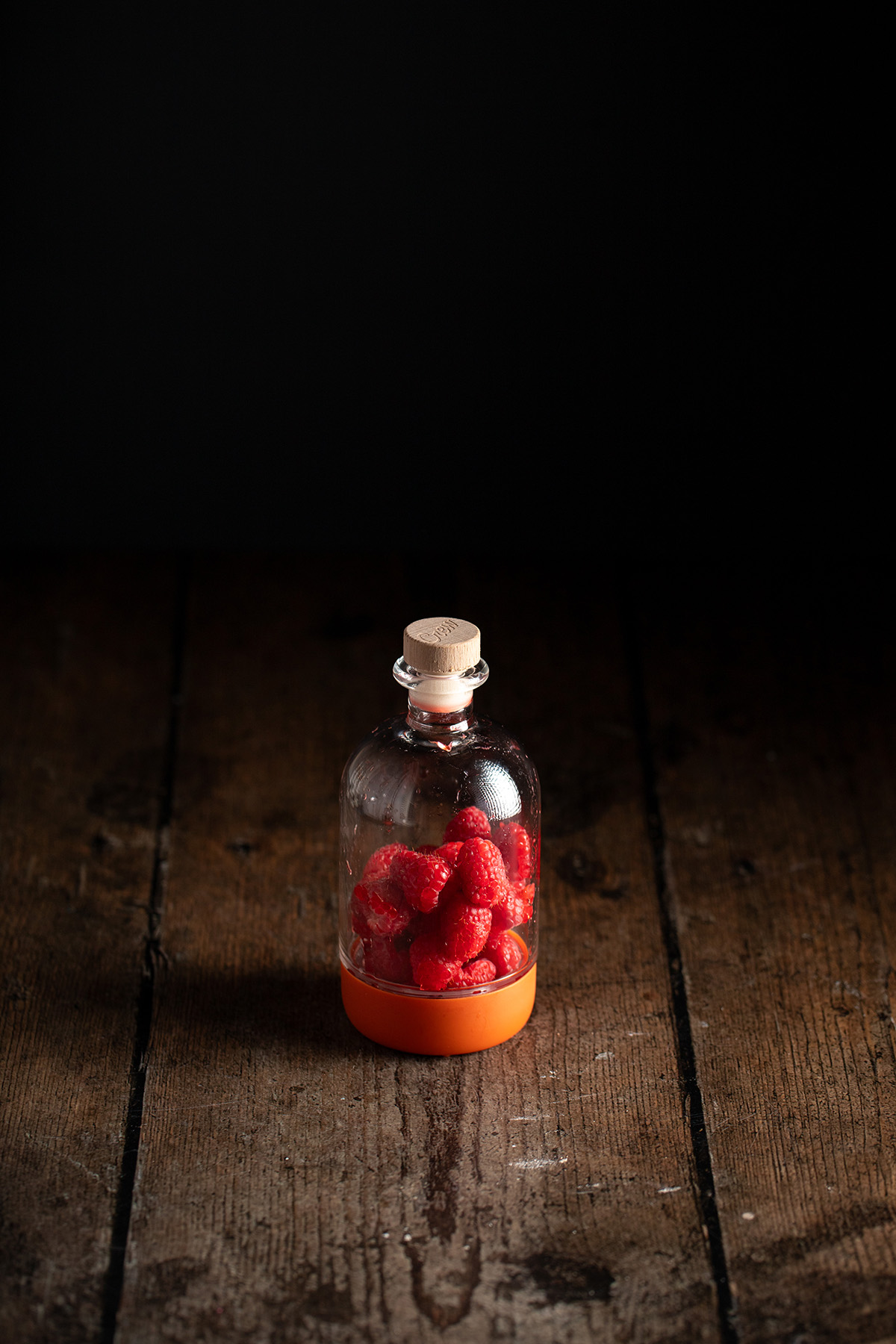 fresh raspberries in a glass bottle.