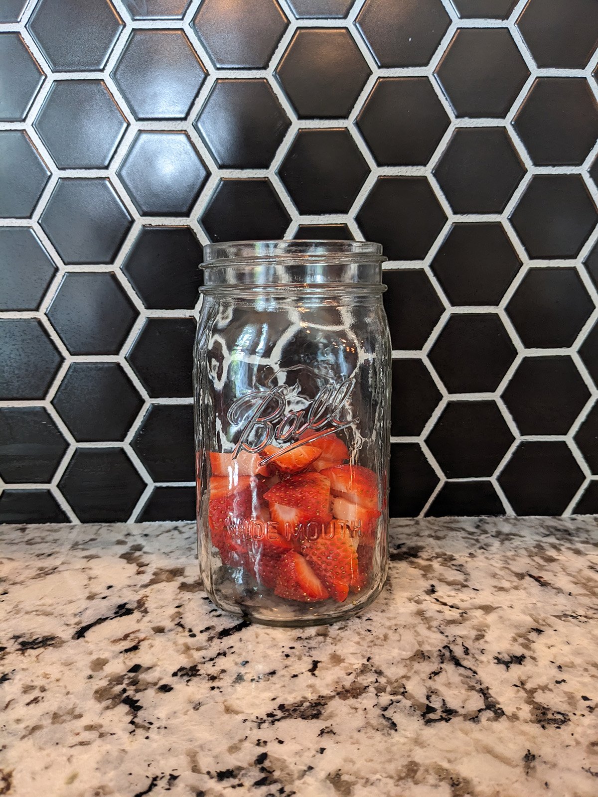 a mason jar full of sliced strawberries.