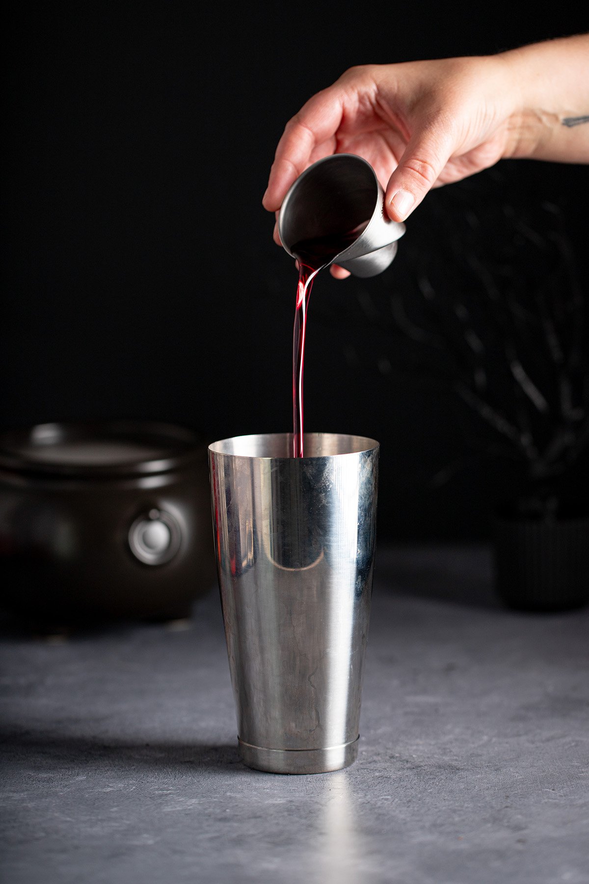cherry simple syrup being poured into a cocktail shaker.