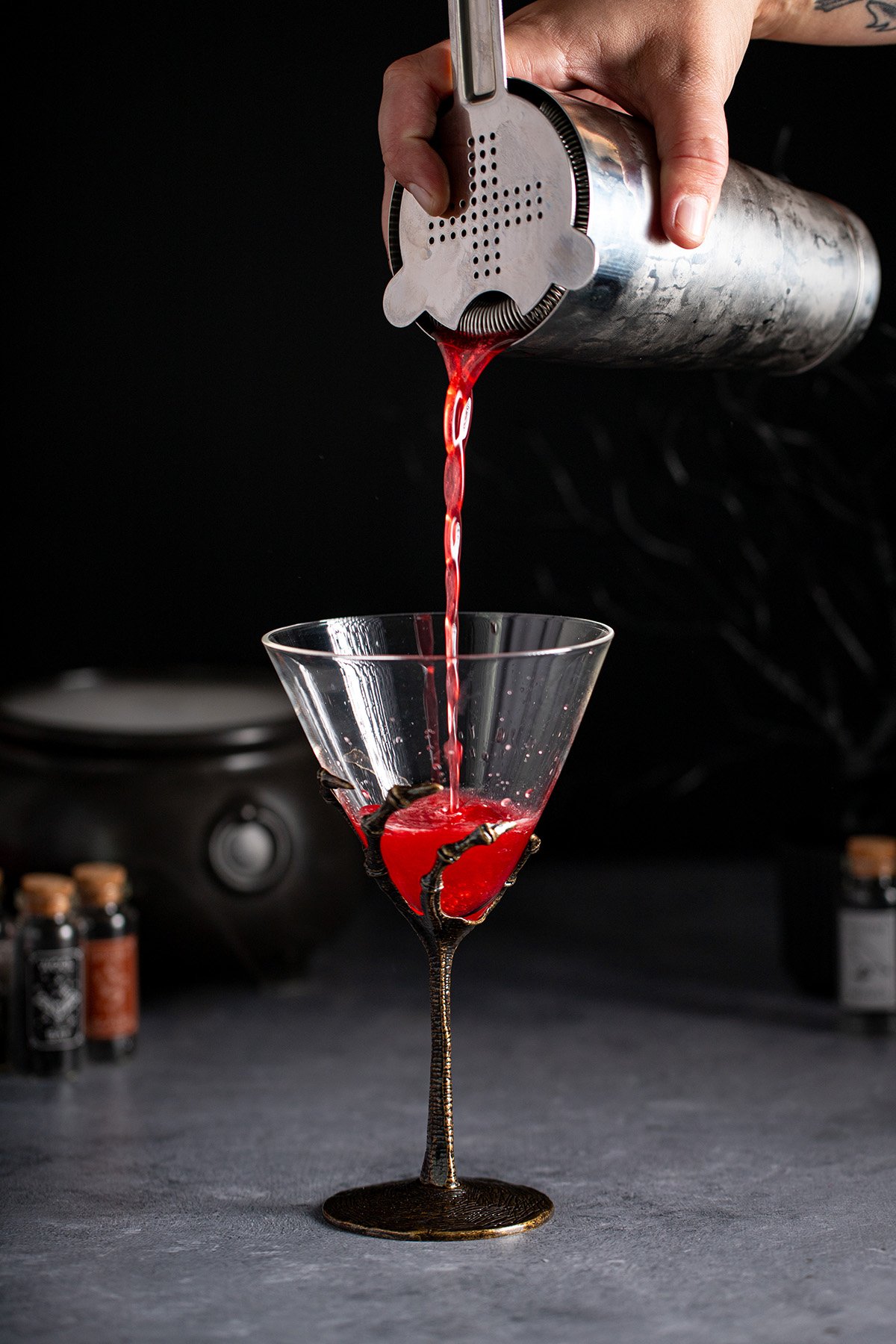 a vampire's kiss martini being strained into a glass.