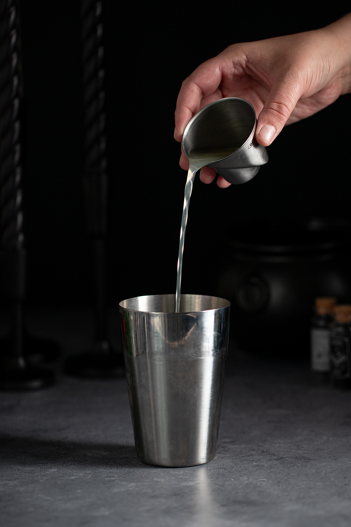 pouring lemon juice into a cocktail shaker.