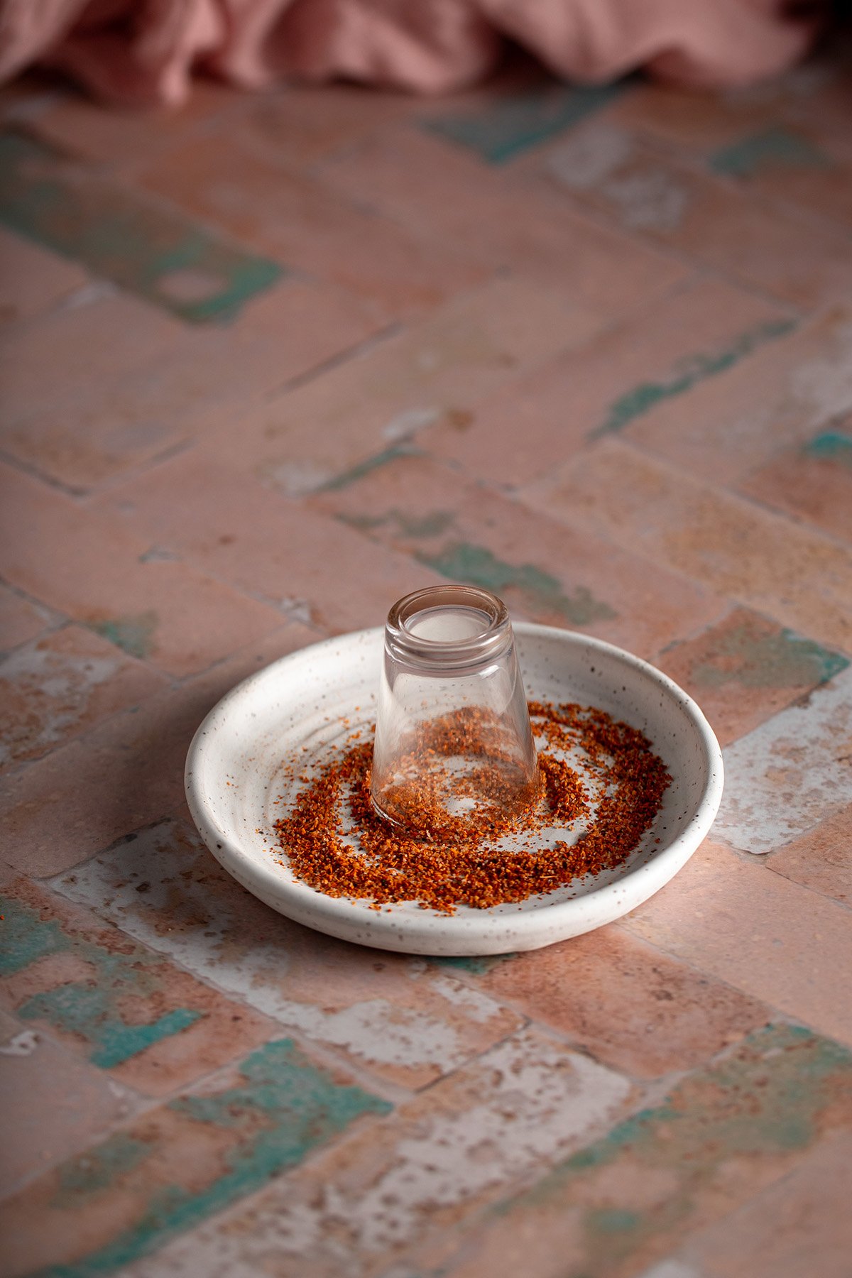 a shot glass turned upside down in a small plate of tajin.