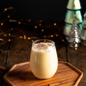 a glass of sous vide eggnog garnished with whipped cream and nutmeg.
