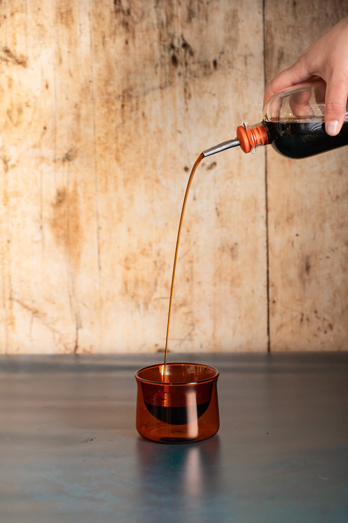 a small bottle of brown sugar syrup being poured into an amber colored glass.