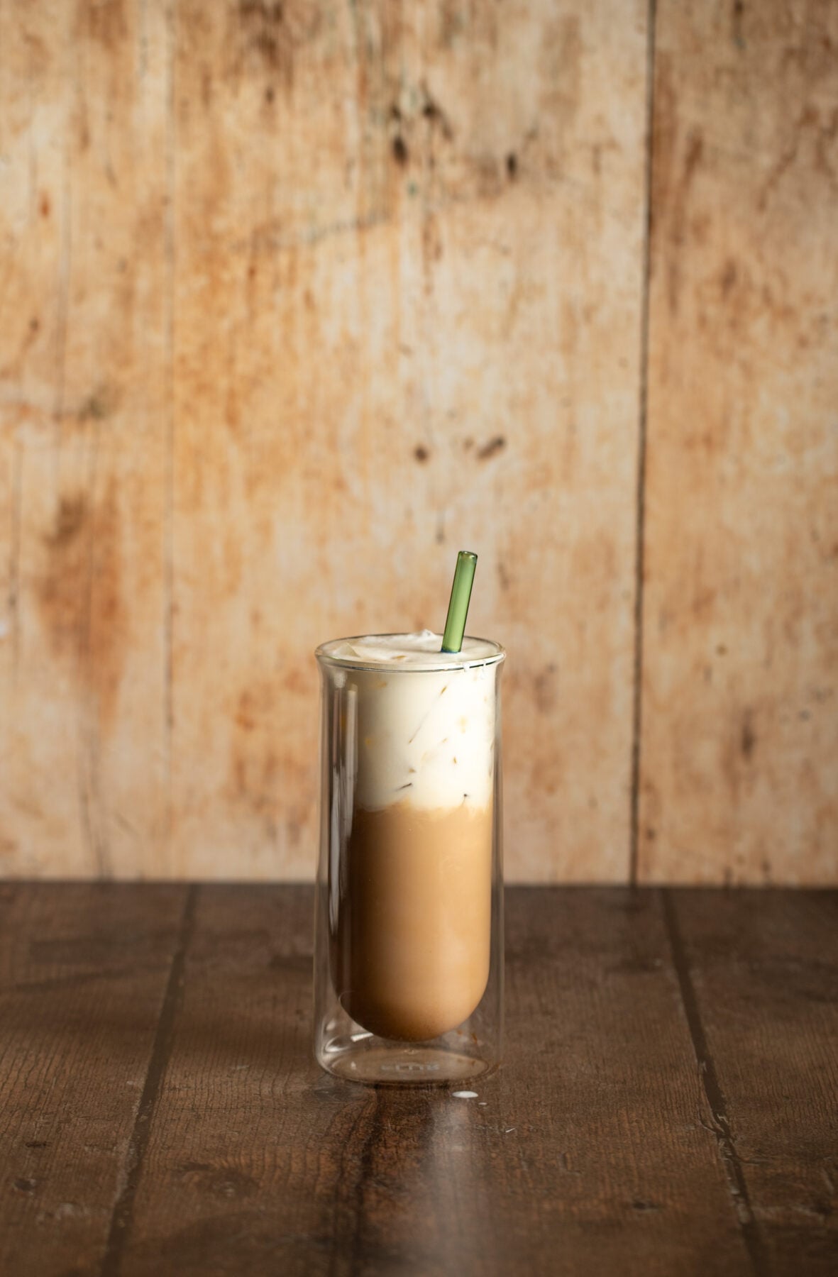 iced carrot cake latte topped with cold foam in a tall clear glass.