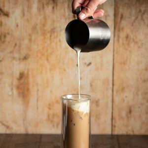 cream cheese cold foam being poured on top of a latte.